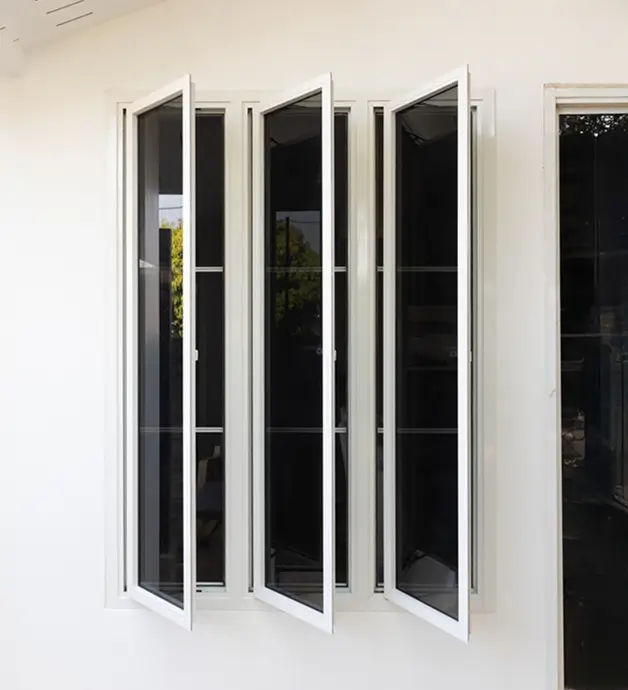 Modern white-framed multi-panel windows with dark tinted glass, partially open against a white wall